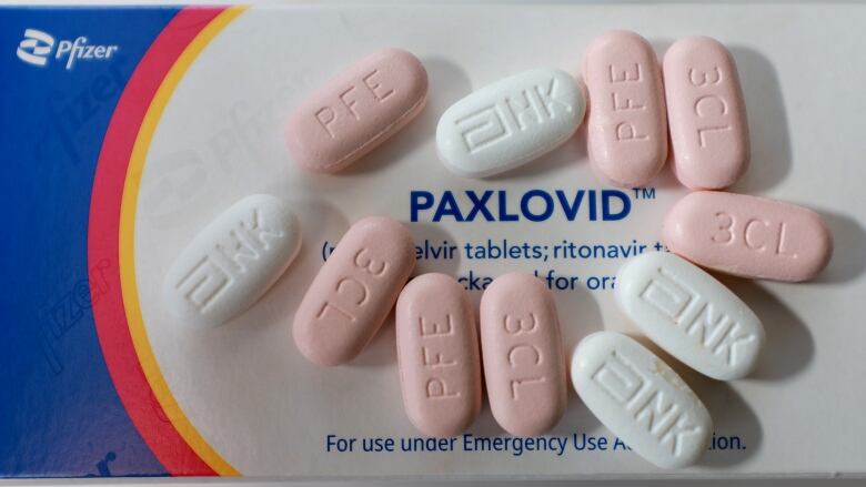 A blue, white, red and yellow box is pictured here with pink and white pills on top.