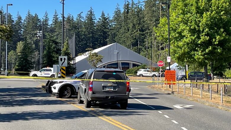 Police vehicles sit behind police tape at South Surrey Athletic Park. 