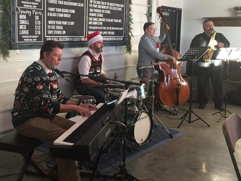 Four men play instruments while wearing Christmas outfits.