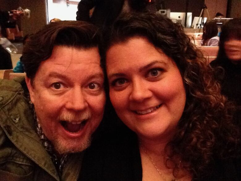 A bearded man and curly-haired woman smile for the camera.