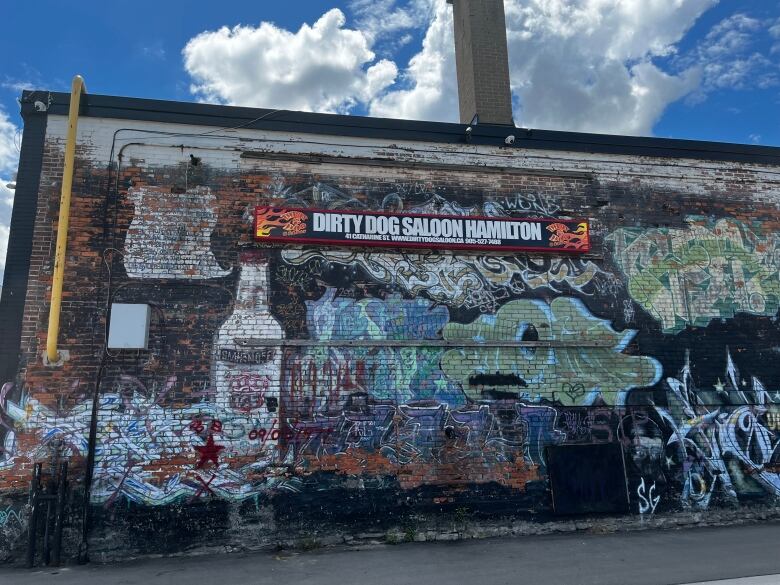 A grafitti'd wall with a sign that says 'Dirty Dog Saloon'. 