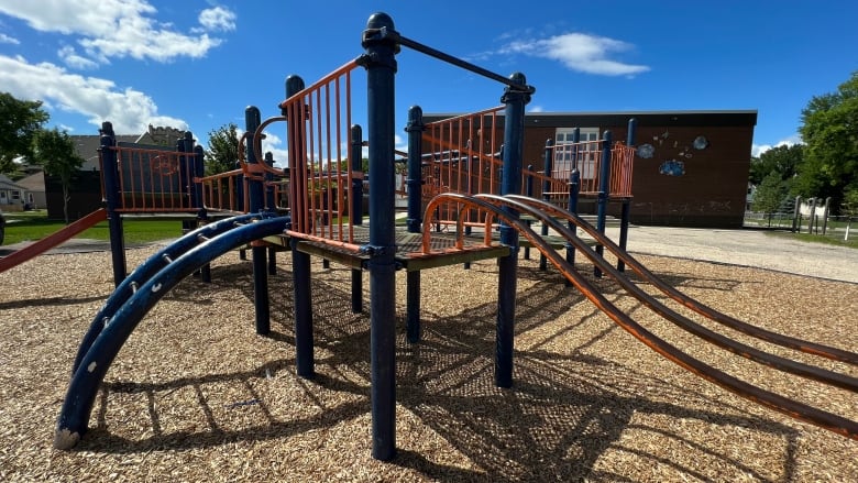 A play structure is shown outside of a school on a sunny day.