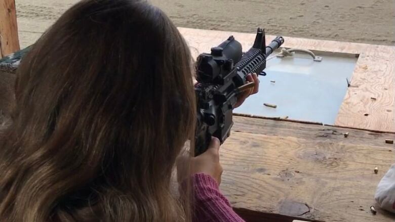 A young target shooter fires an AR-15 at a gun range in Garson, Ontario.