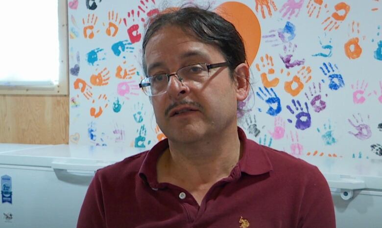 Jasen Benwah sitting in front of a banner that reads Every Child Matters.