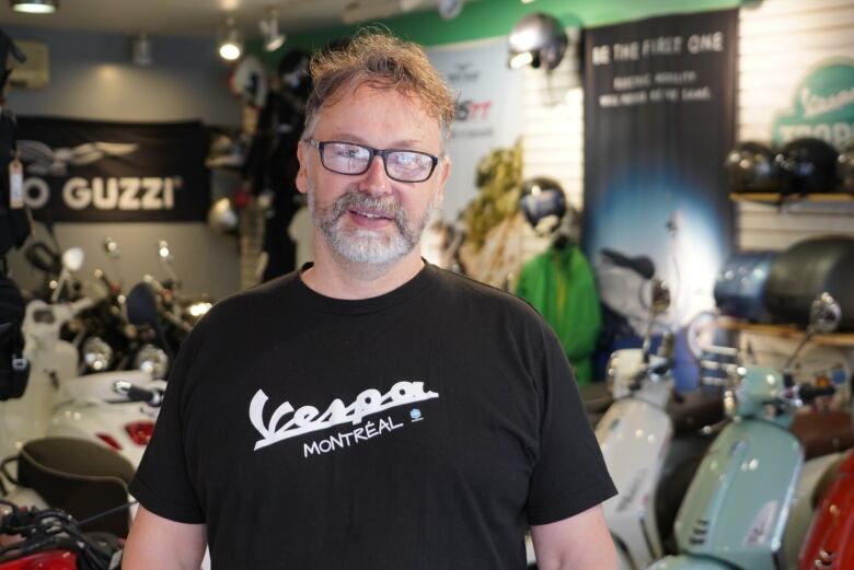 A man stands in a motorized vehicle dealership.