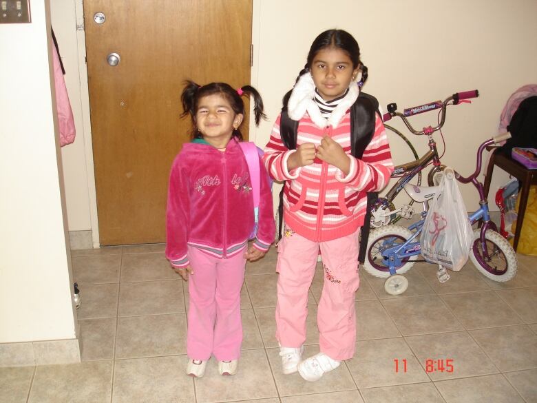 Two girls in pigtails smile for the camera.