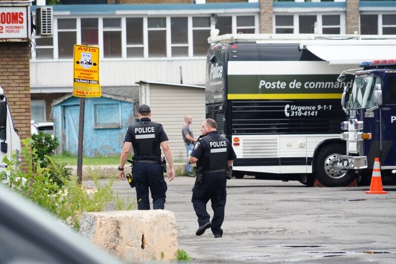 Two police officers and a large SQ truck at a motel.