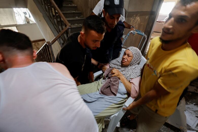 Emergency responders evacuate a woman from a building after an explosion in Gaza City August 5, 2022