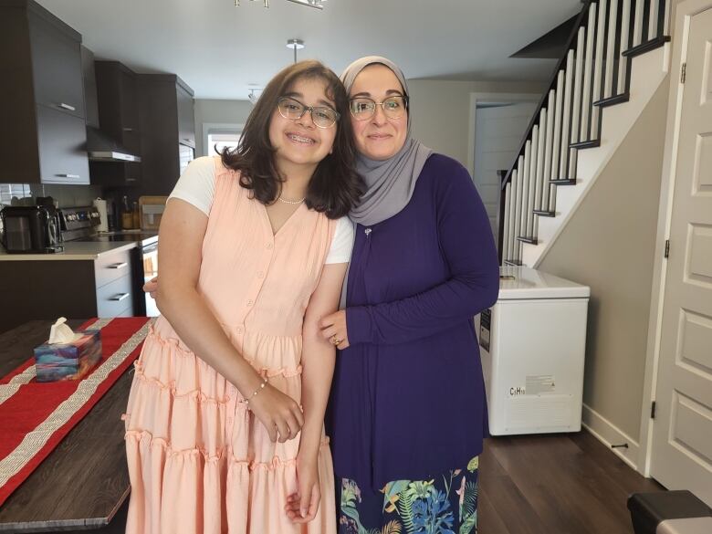 A mother and daughter hug while posing for a photo. 