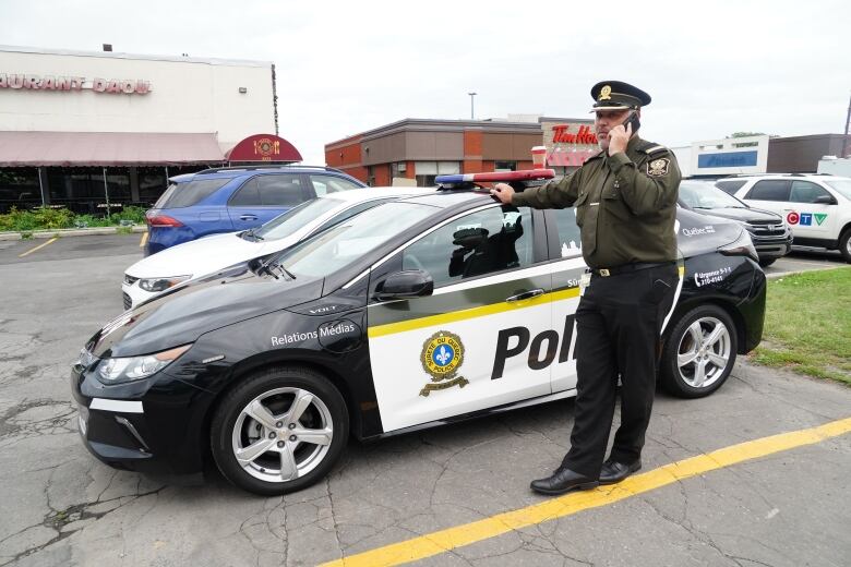 A police officer is standing and talking on the phone. 