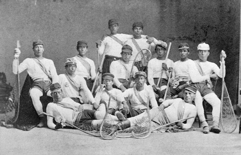 A team of men pose with lacrosse sticks