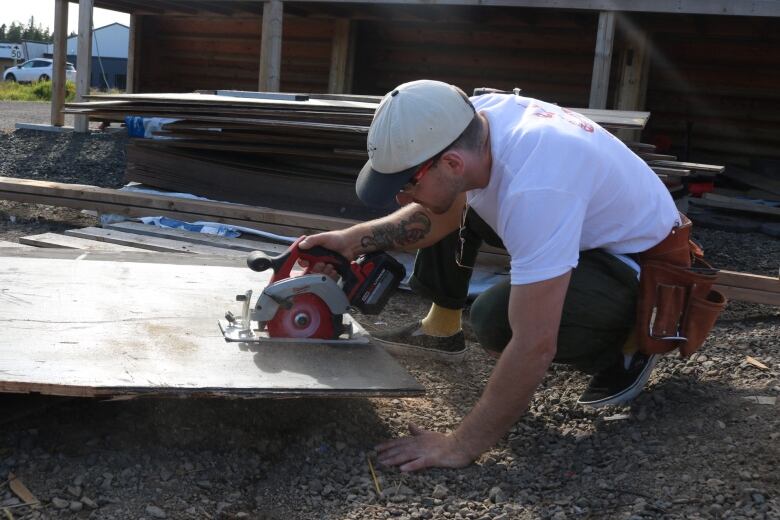 A man uses a circular saw on a piece of wood. 