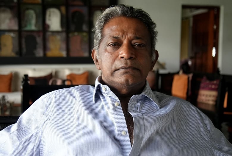 A Sri Lankan man is seated in his home.