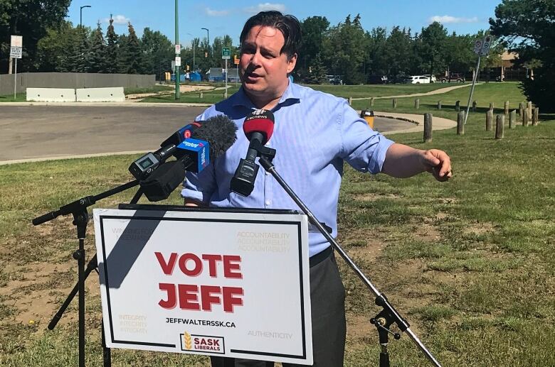 Man speaks at a podium infront of a park