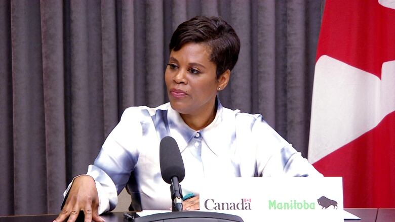 A woman with short hair sits in front of a microphone.