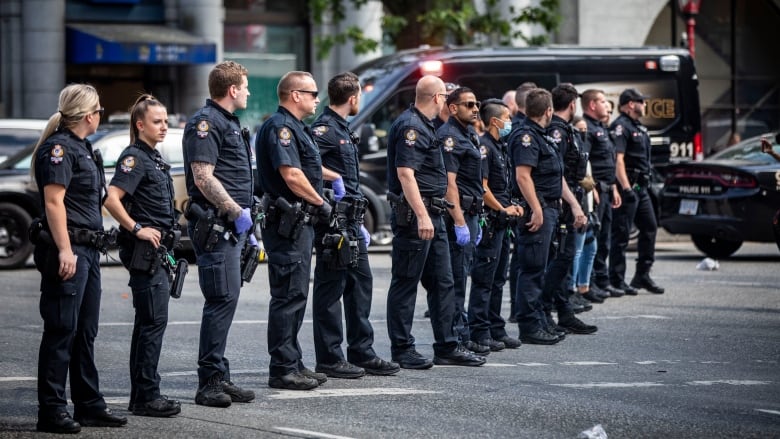 A line of police officers on a street. They look imposing and authoritative.