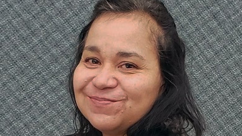 A missing person handout photo provided by RCMP shows a middle-aged Indigenous woman with grey streaks in her hair. She is wearing a black shirt and smiling at the camera.