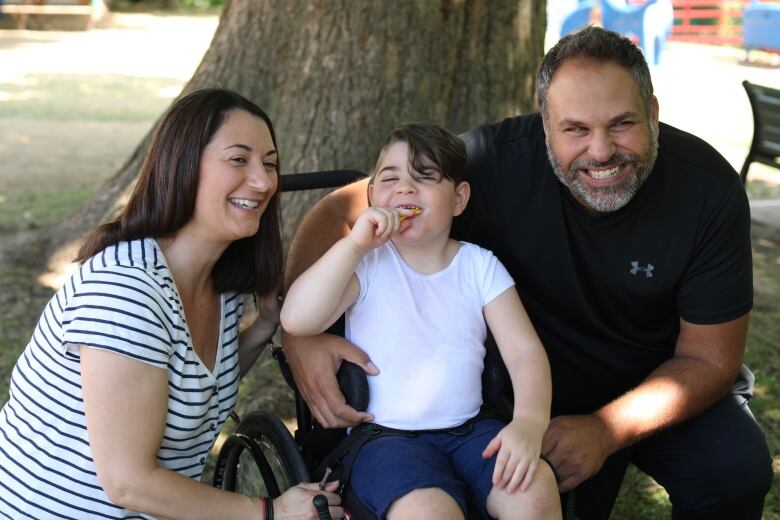 A woman, child, and man smile together.