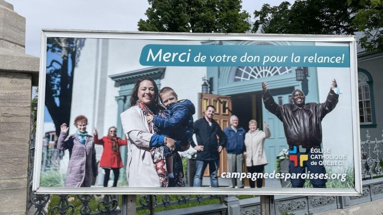 Picture of a billboard with a group of people smiling in front of a church on it.