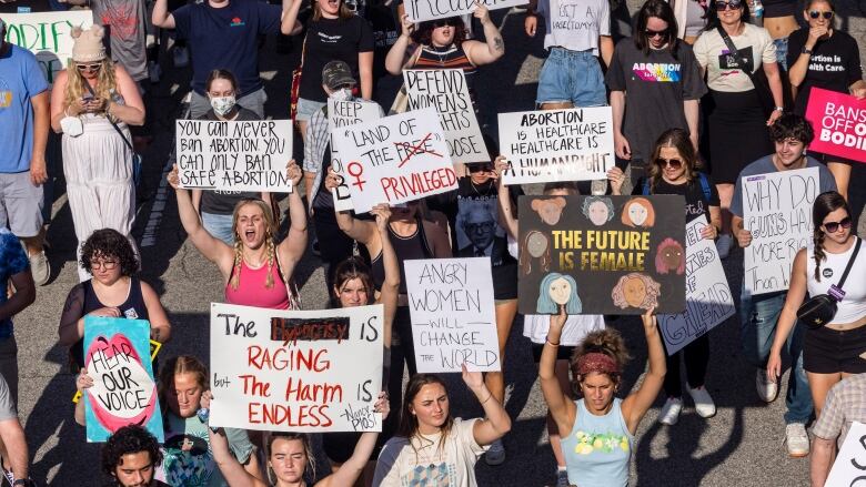 People hold up protest signs.