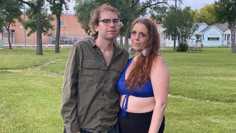 A man and a woman stand beside each other in a park.