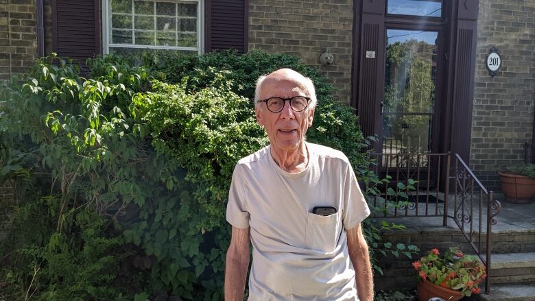 A man, Eklove, stands in front of his home on Glen Cedar Road.