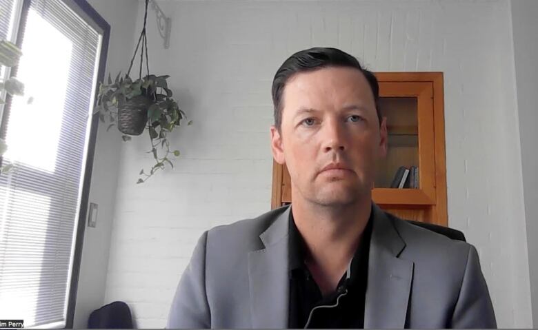 A man sits in a room near a window.