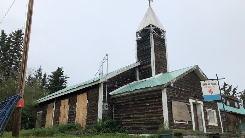 An old log church with a bell tower pictured in the summer.