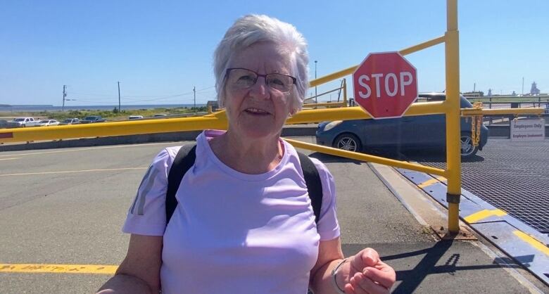 Smiling woman stands in front of ferry dock. 