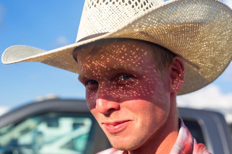 A close up of a  young man wearing a cowboy hat with blue eyes.