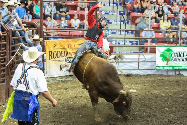 A cowboy wearing a helmet rides a bucking bull.