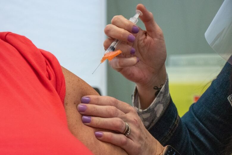 A person puts a needle in another person's arm