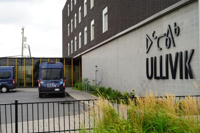 A lodging facility with a sign reading Ullivik. Parked vans are spotted in its parking lot. 