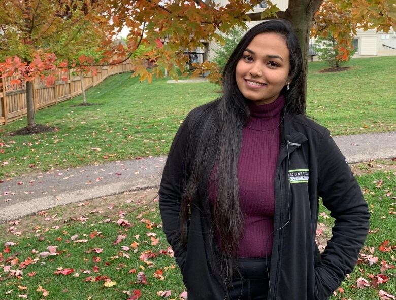 A young woman stands in a yard in the fall.