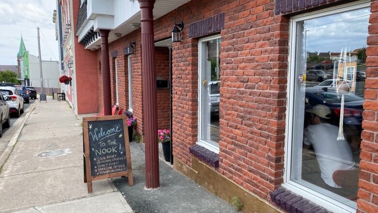 The exterior of a restaurant with a sign welcoming customers. 