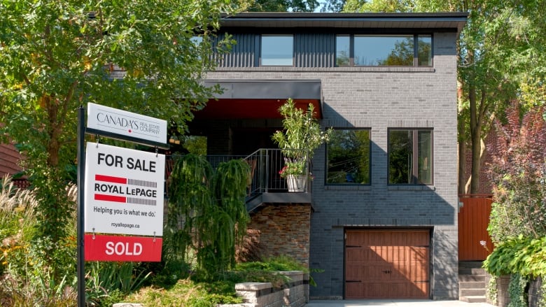 A Royal LePage SOLD signs is posted on the lawn of a home.