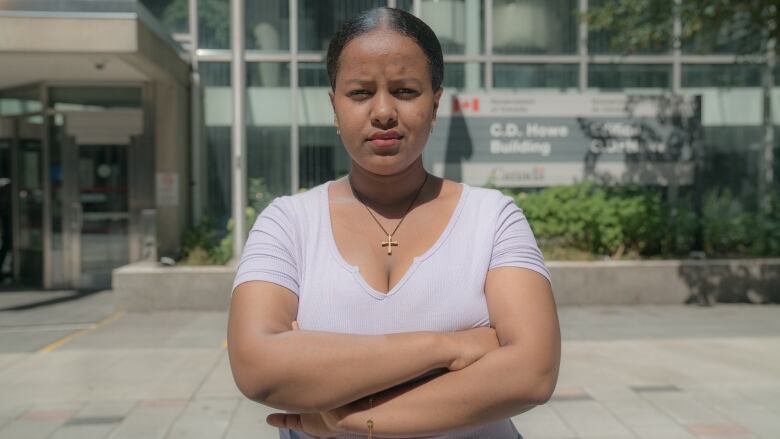 A woman crosses her arms outside a government building.