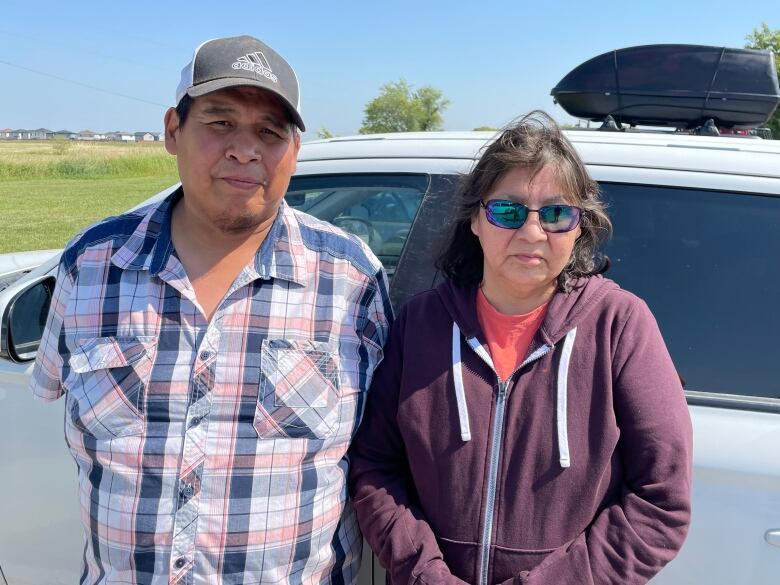 Two people stand in front of a van.