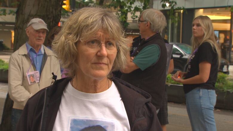 Lisa Weih, a woman with greying hair and round glasses, speaks at a protest.