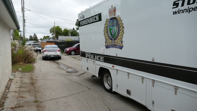 A white police forensics van is parked in a back lane. 