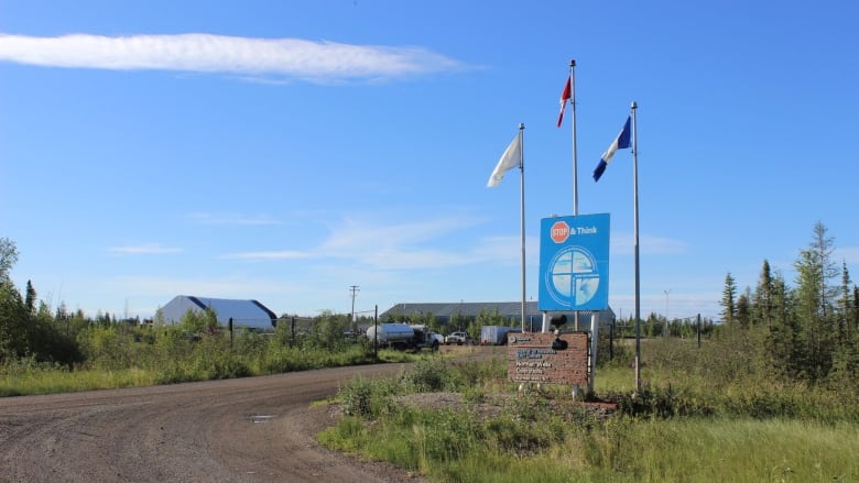 A sign and three flags outside a large building in sunny weather. 