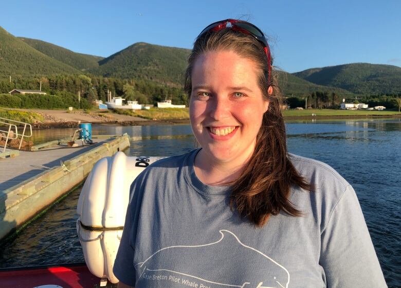 A white woman is seen wearing dark hair in a ponytail and a t shirt with a grey whale on it. 