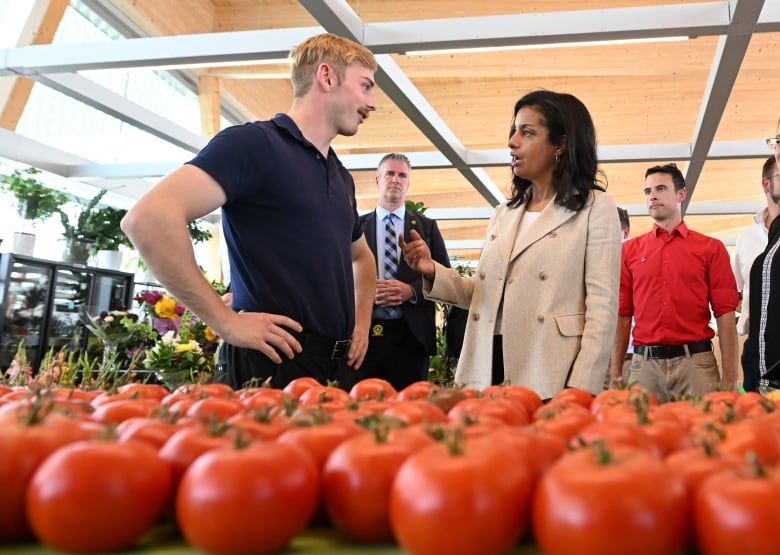 Quebec Liberal Leader Dominique Anglade speaks with a producer during a campaign stop at a farmers' market in Quebec City on Monday.