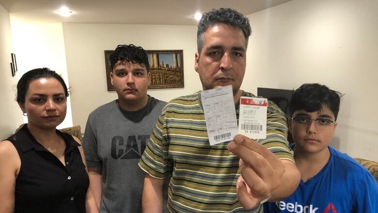 Moe Abdollahi holds the claim checks that go with the luggage that has been lost on a recent Air Canada flight. His family stands next to him. 