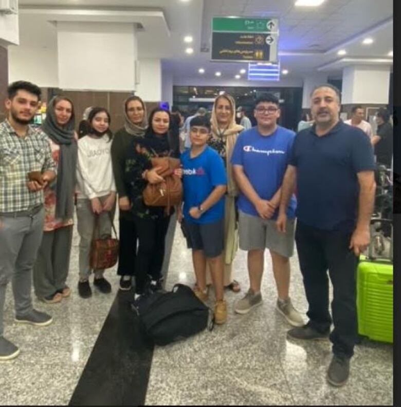 A group shot of Moe Abdollahi at an airport overseas reveals a lime green suitcase at Abdollahi's feet, one of the missing bags.