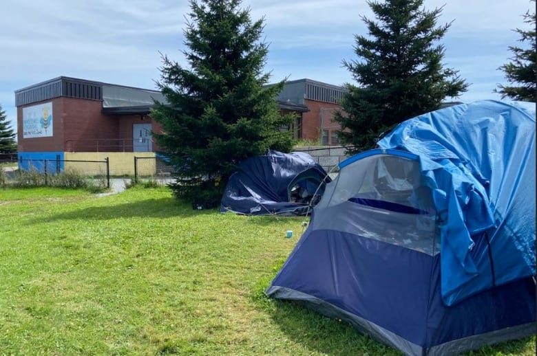 Tents sit on the grass behind a school