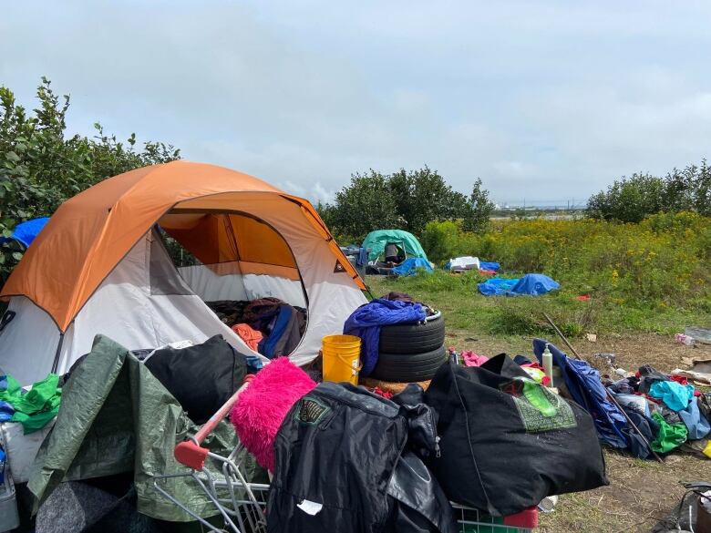 A tent encampment with a pile of belongings outside it