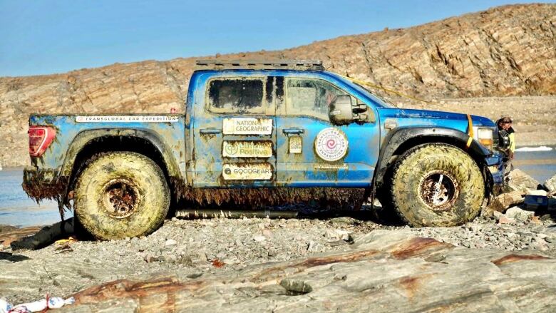 A big blue truck covered in mud. 