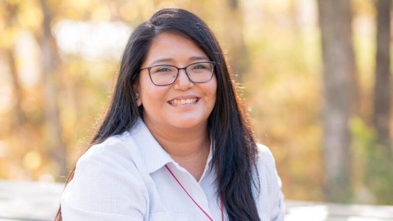 A women in a white shirt wearing a red necklace sits on a picnic table.