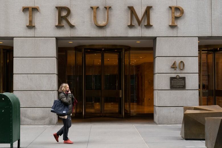 A person walks by a building with the word Trump written across it. 